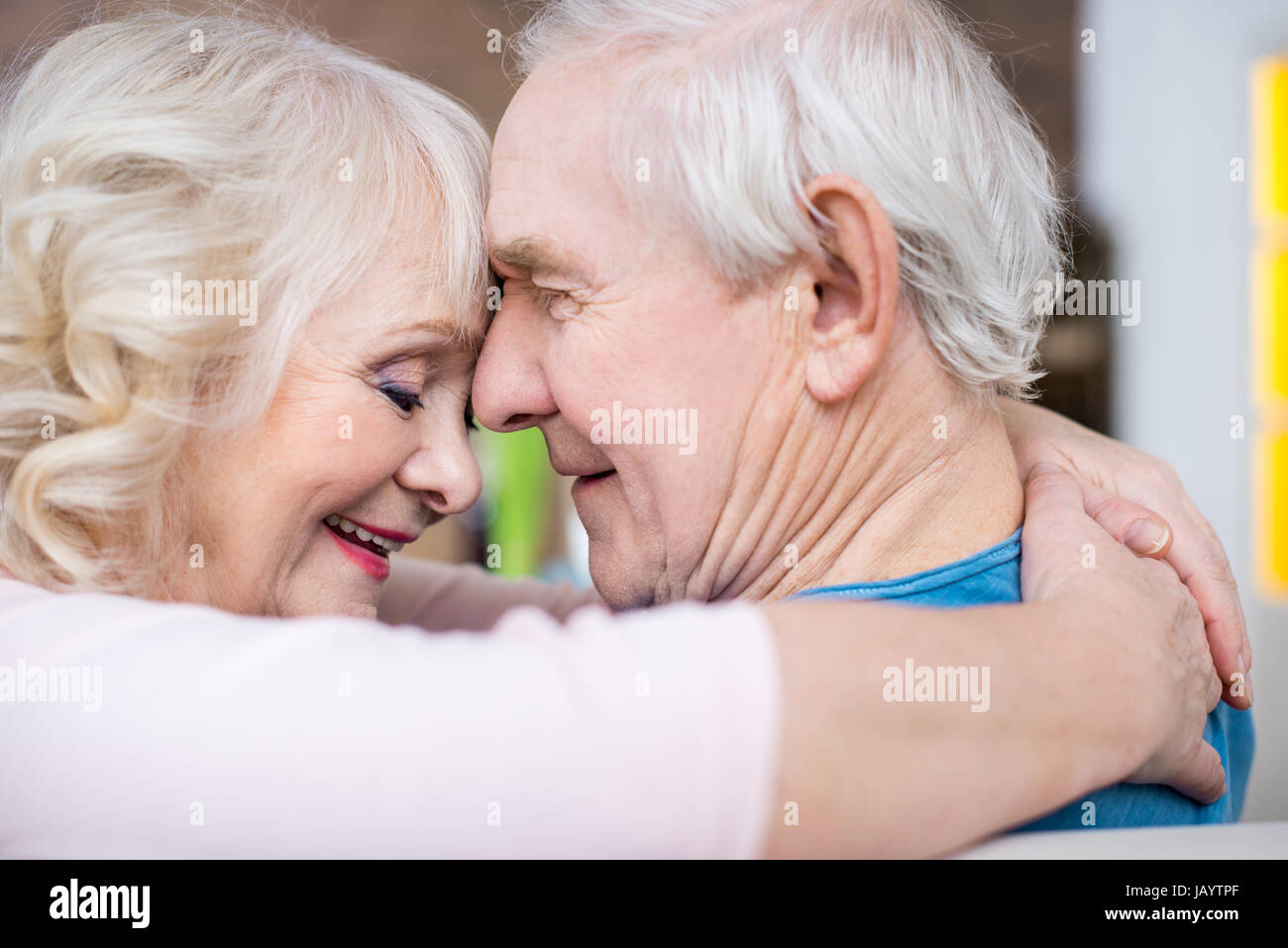 Happy senior couple embracing et toucher leur front à la maison Banque D'Images