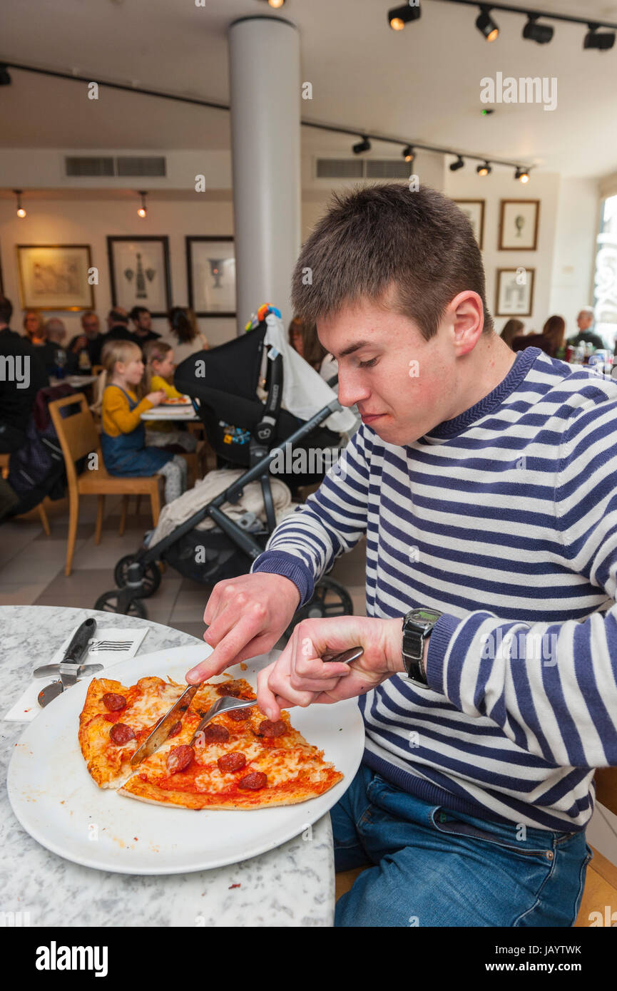 Un garçon de 17 ans de manger une pizza dans un restaurant au Royaume-Uni Banque D'Images