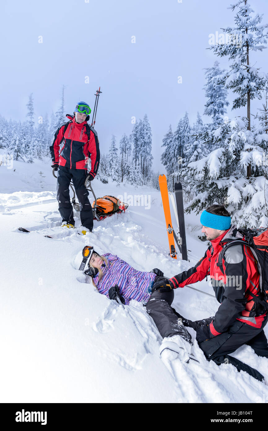 Aider patrouille de ski femme avec jambe cassée gisant dans la neige Banque D'Images