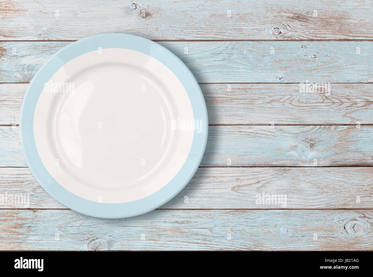 Assiette vide blanc avec bordure bleue sur table en bois Banque D'Images