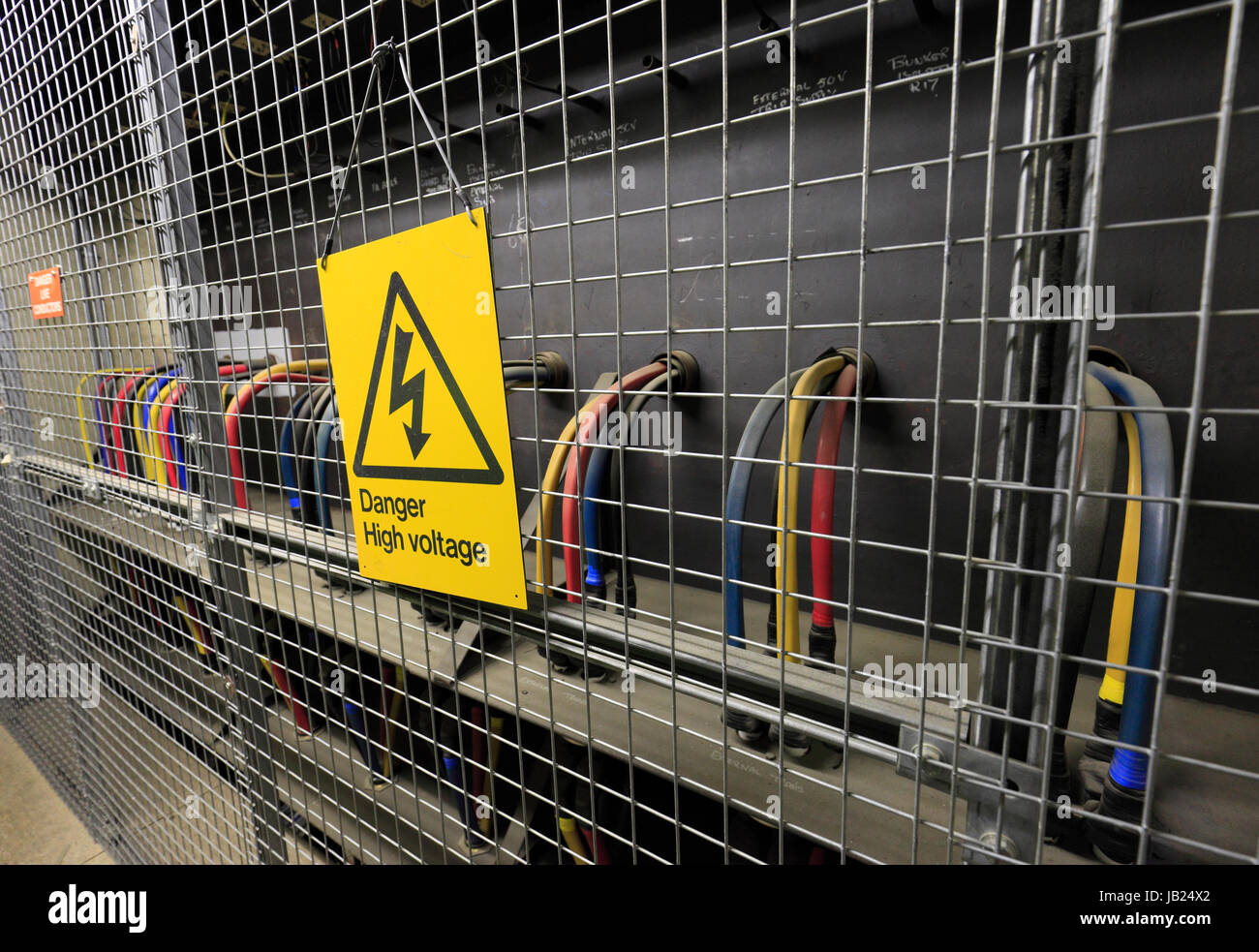Les câbles derrière une cage de protection et un panneau d'avertissement de tension élevée. Banque D'Images