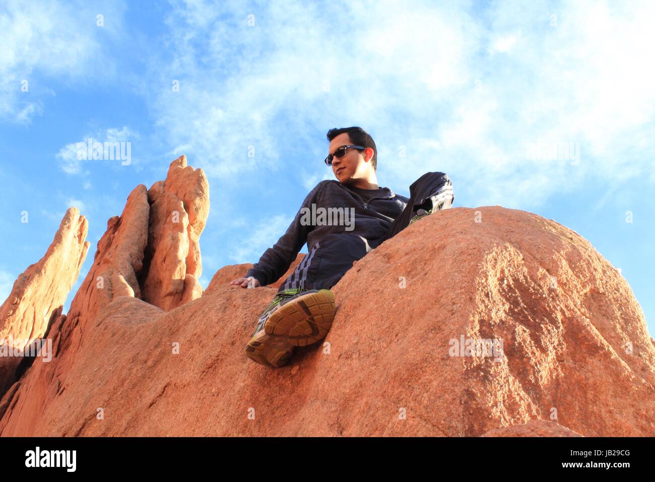 Un jeune homme assis dans une montagne Banque D'Images