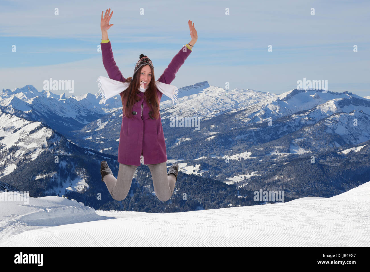 Junge Frau springt vor Glück und Freude im Winter im Schnee in den Bergen Banque D'Images