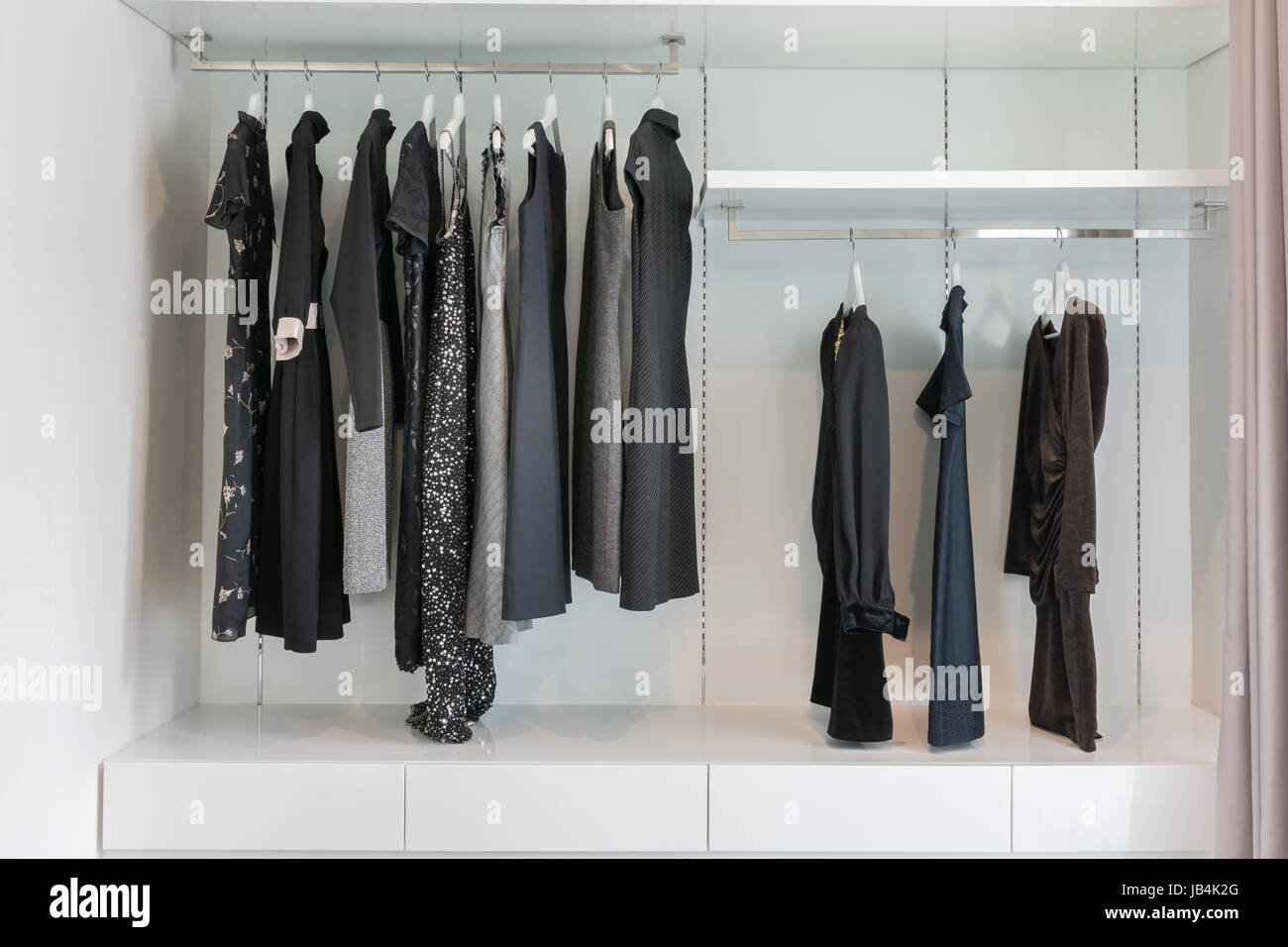 Penderie moderne avec rangée de robe noire accroché sur cintre dans une armoire. Banque D'Images