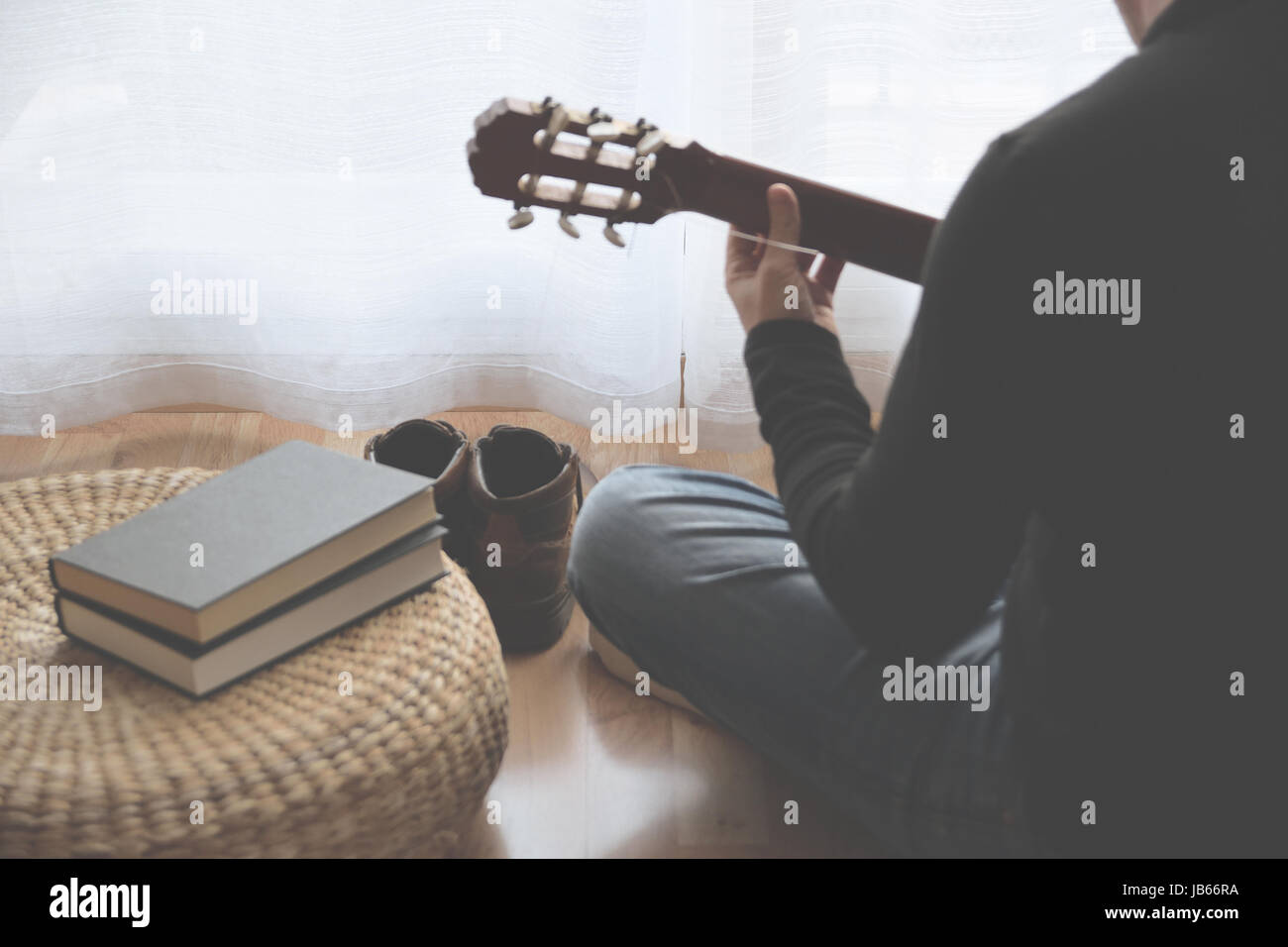 Jeune homme jouant de la guitare après avoir lu un livre. Copie de l'espace pour l'éditeur de texte. Banque D'Images