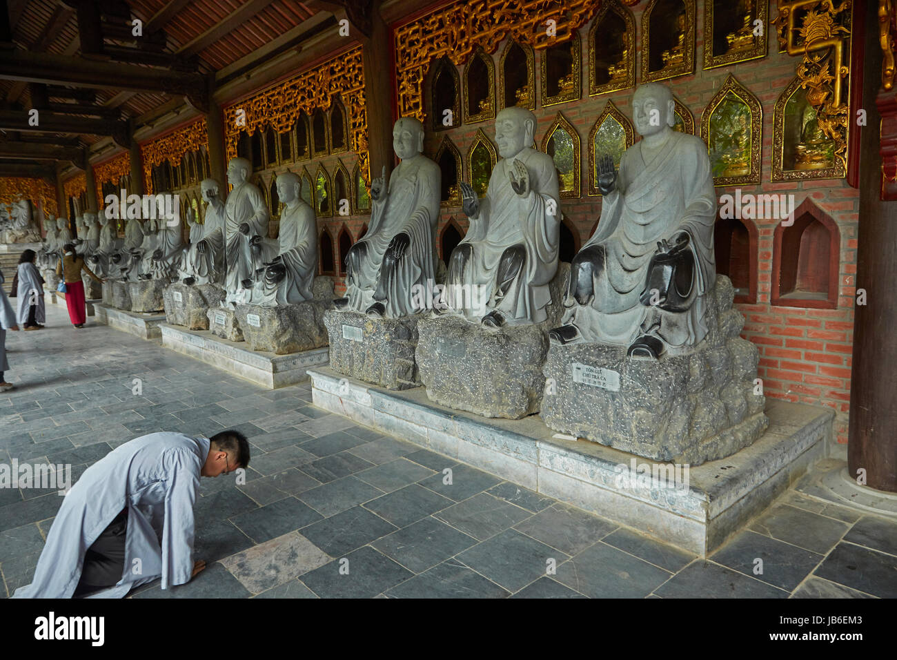 Homme qui prie par rangée de statues Arhat, Bai Dinh Buddist Temple complexe, près de Ninh Binh, Vietnam Banque D'Images