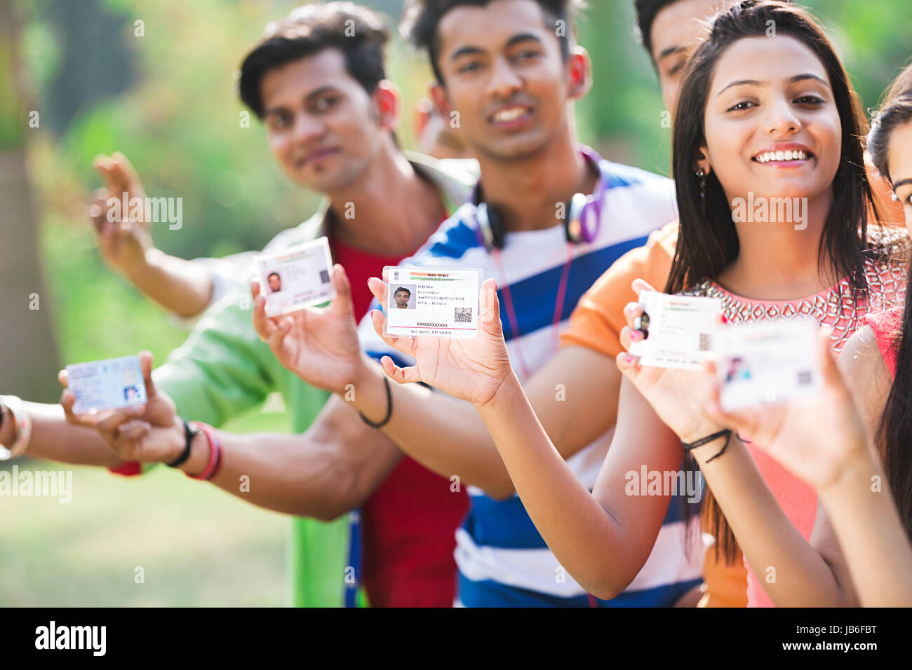 Groupe indien adolescent filles et garçons d'attente permanente et montrant une carte d'identité aadhaar gouvernement in park Banque D'Images