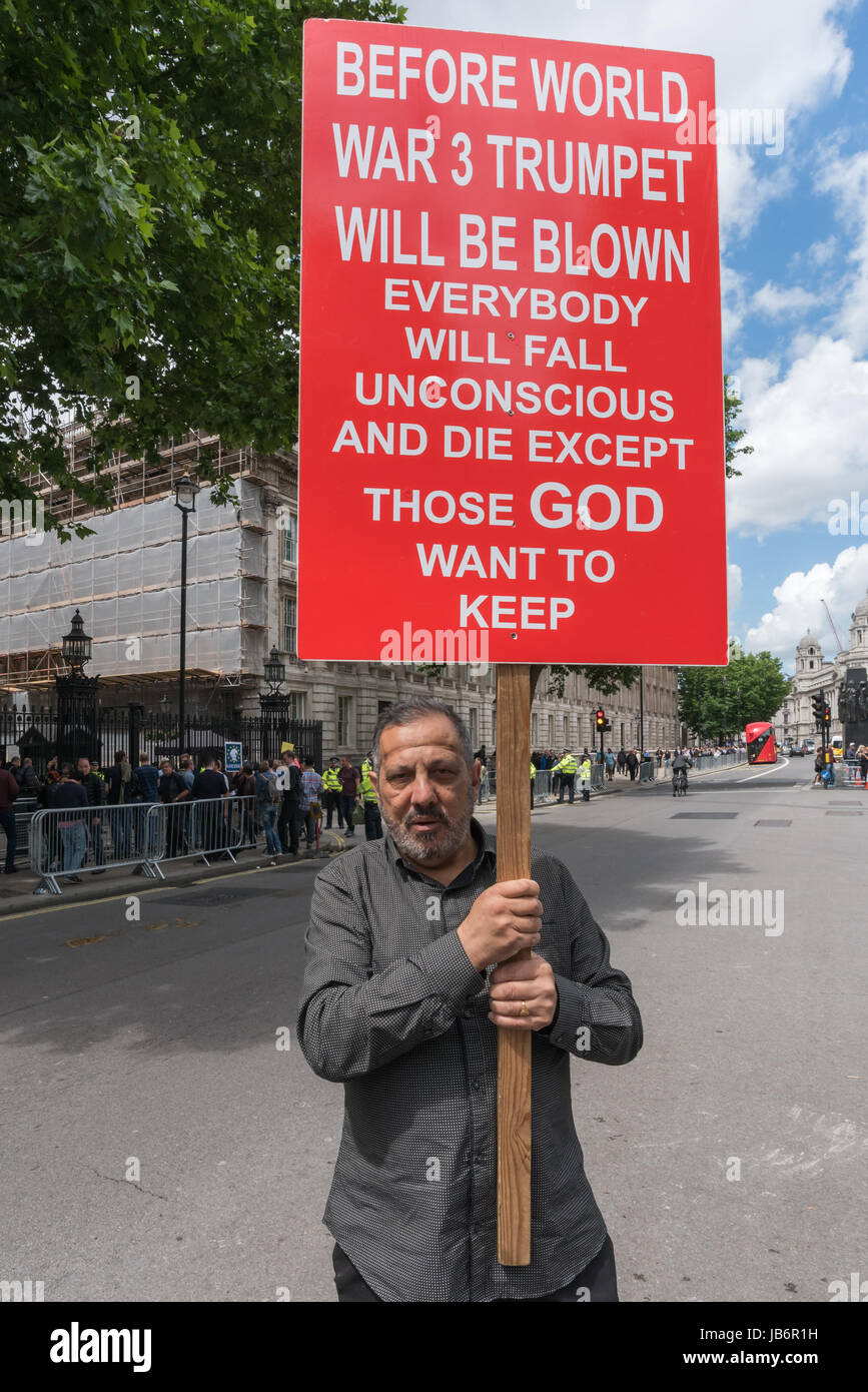 Londres, Royaume-Uni. 9 juin 2017. Après les résultats des élections ont montré qu'aucun parti n'avait la majorité, les manifestants sont venus à Westminster pour exiger que Theresa peut démissionner. Elle a l'intention de rester et d'essayer de gouverner, en s'appuyant sur les votes de la DUP, Parti lié à des paramilitaires loyalistes. Un manifestant à Downing St détient un grand placard double face aux dangers de la guerre mondiale 3, qui va tuer tout le monde sauf ceux que Dieu 'à conserver. Credit : ZUMA Press, Inc./Alamy Live News Banque D'Images