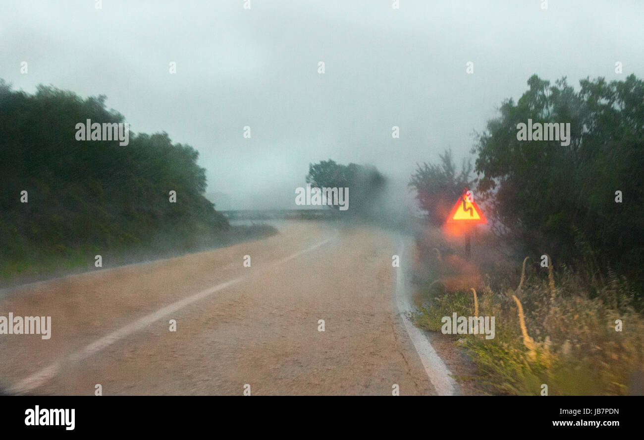 Route de montagne avec un coude gauche marche arrière par iluminated de voiture un jour de pluie. Banque D'Images