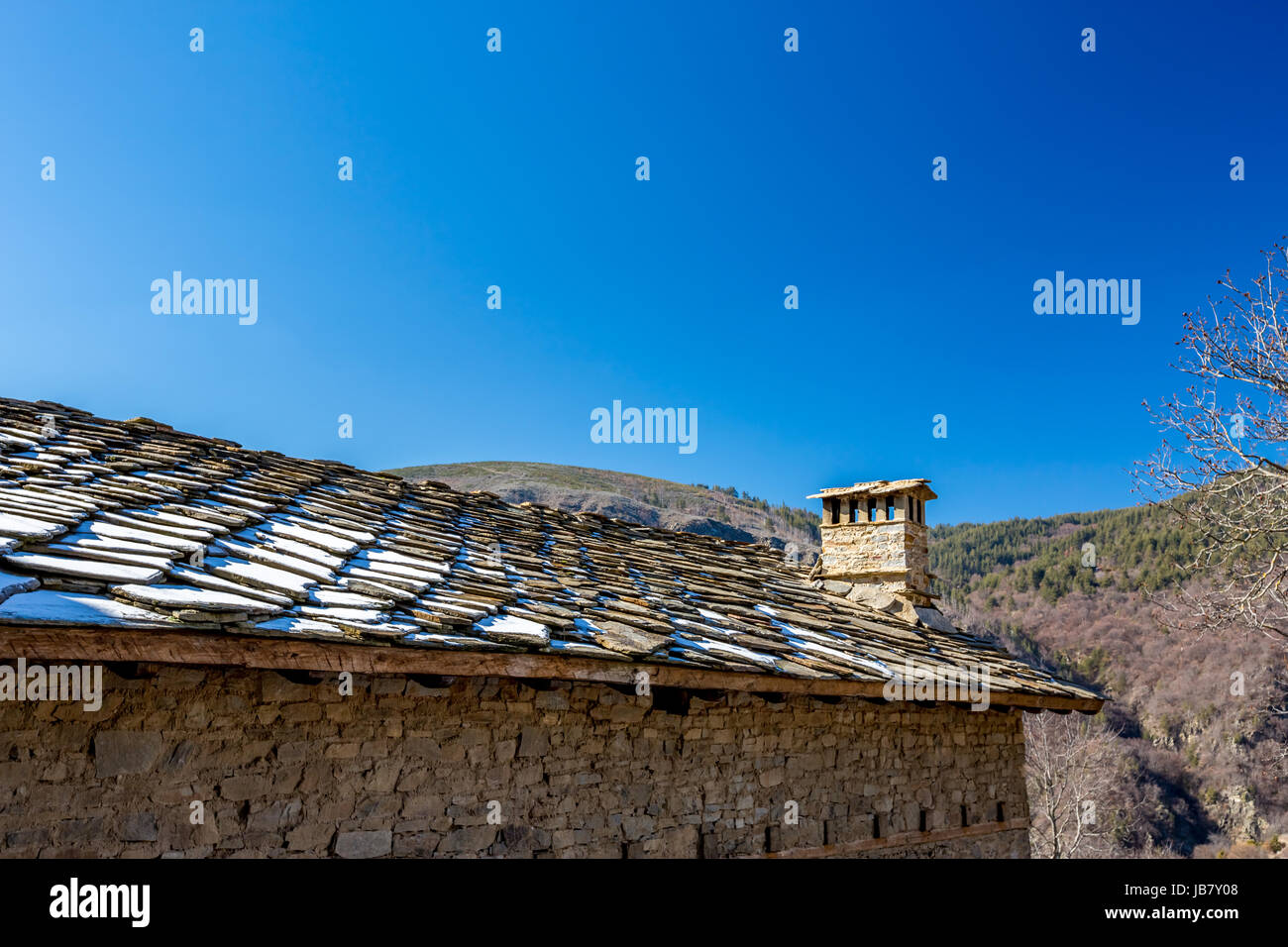 Toit en pierre, ciel bleu, neige et cheminée Banque D'Images