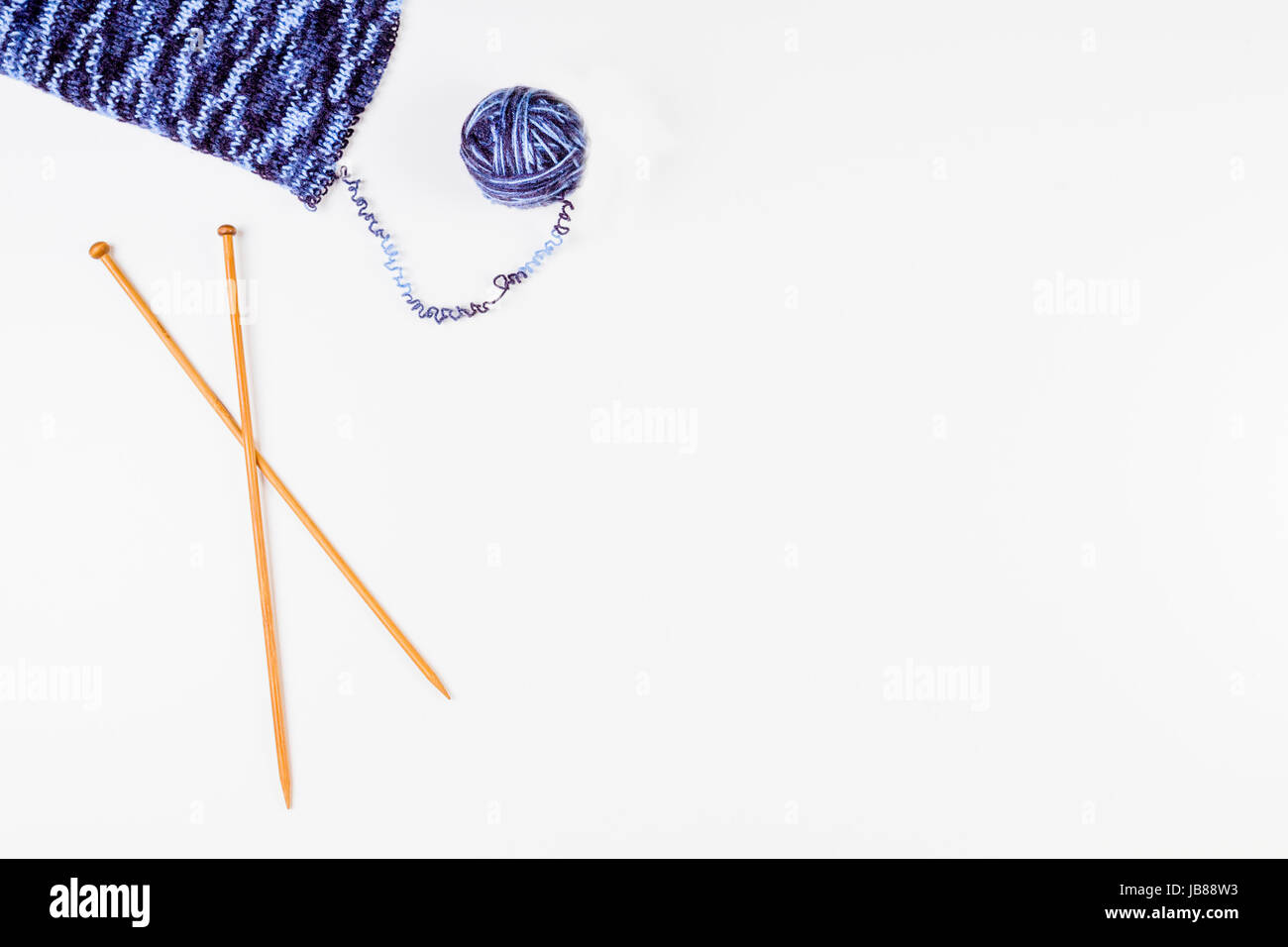 Pelote de laine et tricot avec des aiguilles à tricoter en bois sur fond blanc. Vue d'en haut Banque D'Images