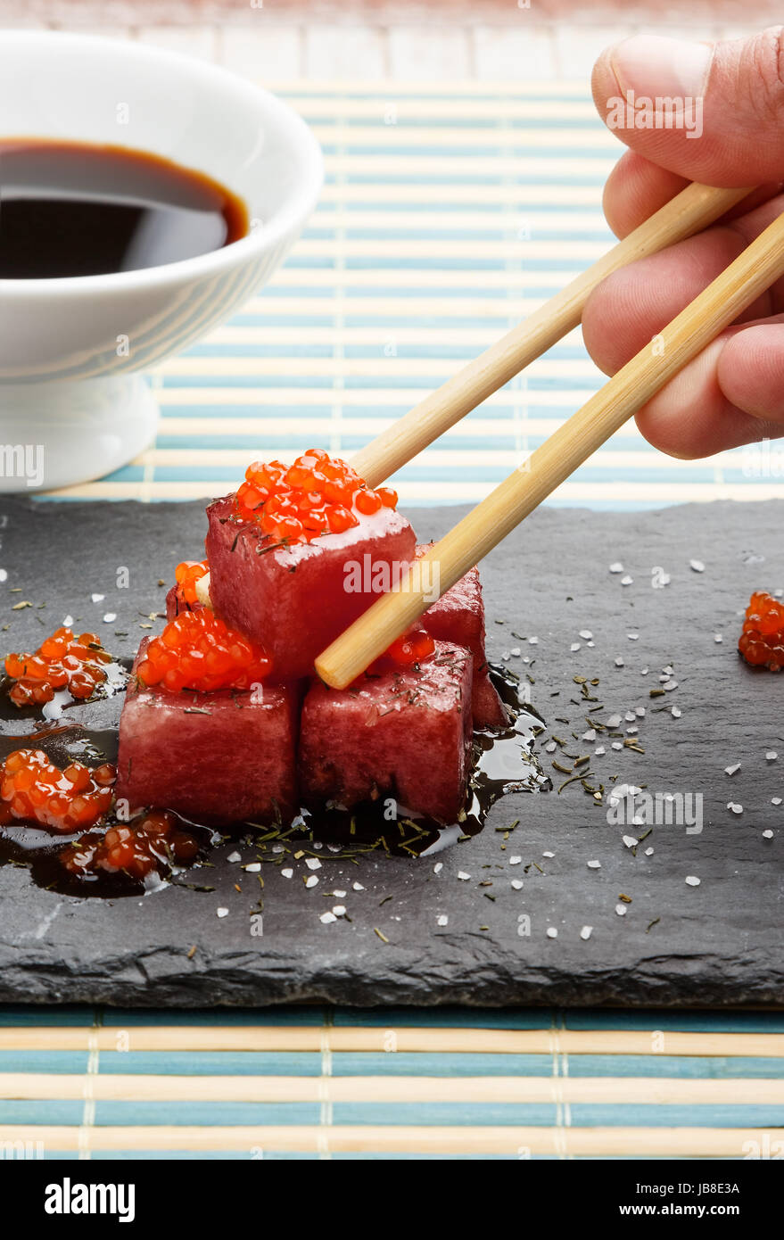 Feux de sashimi de thon dans la sauce de soja avec des oeufs de saumon, l'aneth et le sel épais sur ardoise avec des baguettes et bol avec le soja. Les poissons crus dans un Japane Banque D'Images