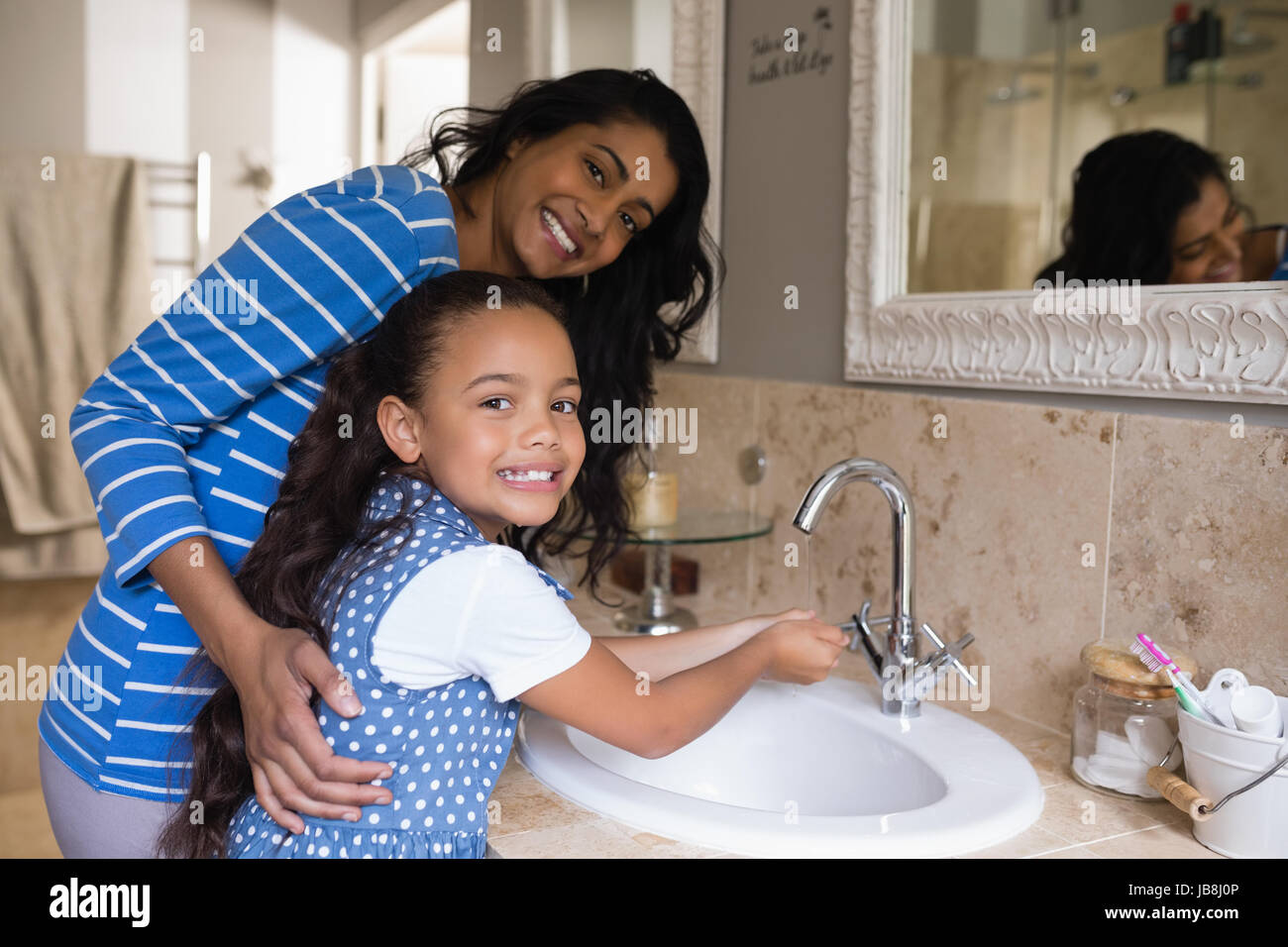 Portrait of smiling girl avec mère lave-mains à l'évier de salle de bains Banque D'Images