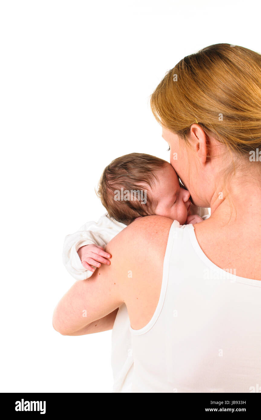 Erwachsene Eine Frau mit weißem Shirt hält einen weiß les gekleideten Säugling zärtlich auf dem Arm, freigestellt Hintergrund weißem vor. Banque D'Images