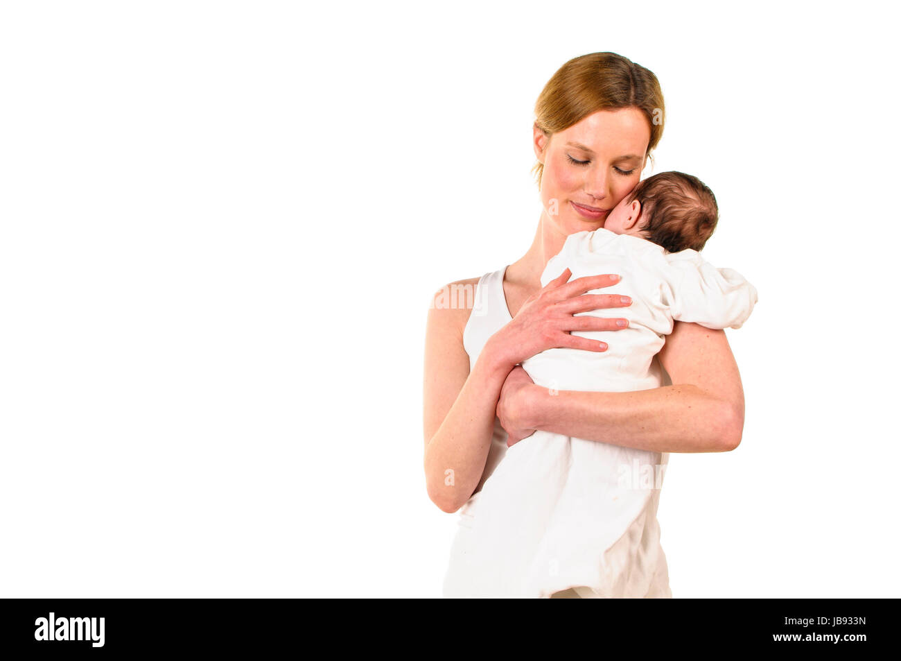 Erwachsene Eine Frau mit weißem Shirt hält einen weiß les gekleideten Säugling zärtlich auf dem Arm, freigestellt Hintergrund weißem vor. Banque D'Images