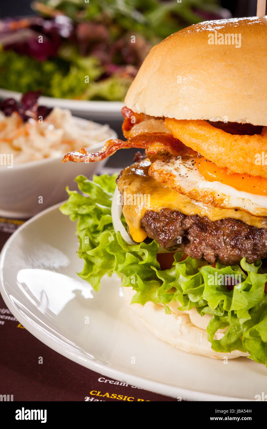 Cheeseburger Hamburger êtes ravi mit Speck und ae salat auf einem Teller Banque D'Images