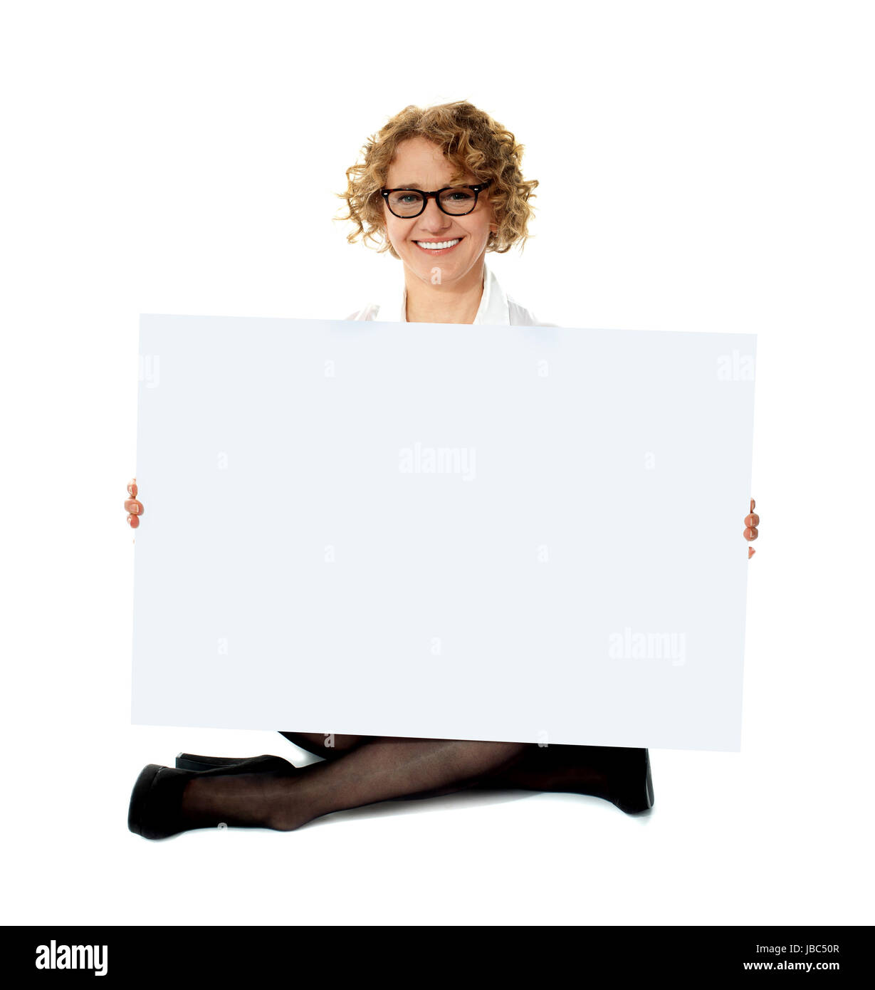 Employée holding white blank banner ad assis sur le sol, jambes croisées Banque D'Images