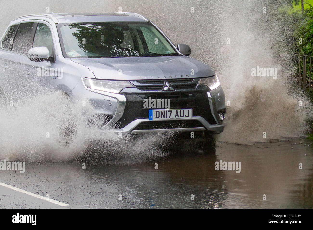 Spray de route en mouvement 2017 Mitsubishi Outlander 5HS PHEV CVT SUV voiture électrique conduisant sur des routes inondées à Tarleton, Lancashire, Royaume-Uni. UK Météo. Inondations après pluie torrentielle rendant difficile la conduite. Après une forte averse, la visibilité était extrêmement limitée, avec des flaques d'eau, de l'eau de surface et un risque d'aquaplaning, avec une perte conséquente de traction et de réaction de la direction. Banque D'Images