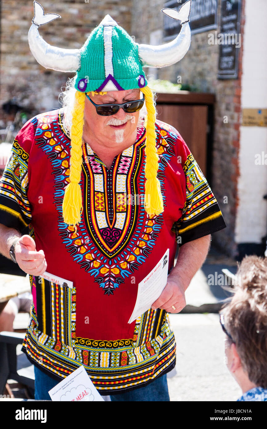 L'Angleterre, Sandwich. Le week-end événement. Âge moyen, grand homme, dans les lunettes de soleil, l'attente sur les tables, habillées de casque Viking tricoté et golden fake cheveux écluses pendant vers le bas. Banque D'Images