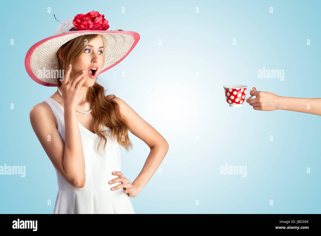 Une photo d'une pin-up girl in vintage hat excité de voir une main avec la tasse. Banque D'Images