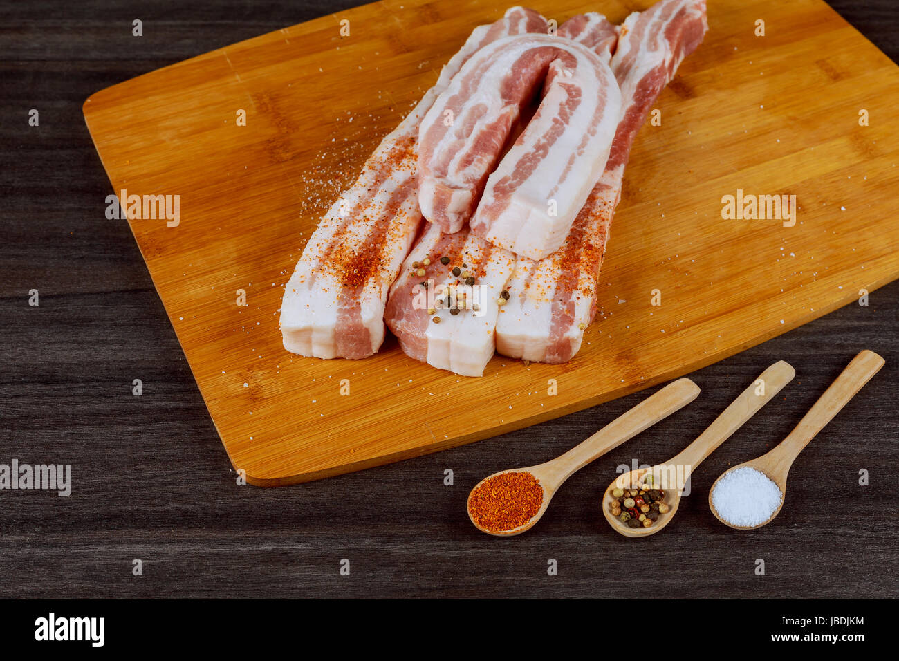 La graisse de porc crus frais prêt à être gammoning sur planche à découper en bois, d'épices et fines herbes. La graisse de porc crus tout préparer pour saler. Banque D'Images