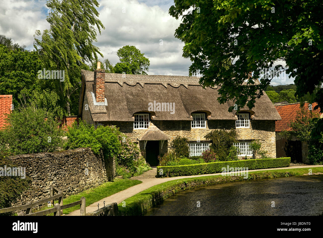 Un anglais pittoresque maison de chaume assis à côté d'un ruisseau dans la charmante ville de Yorkshire Thornton-le-Dale. Banque D'Images