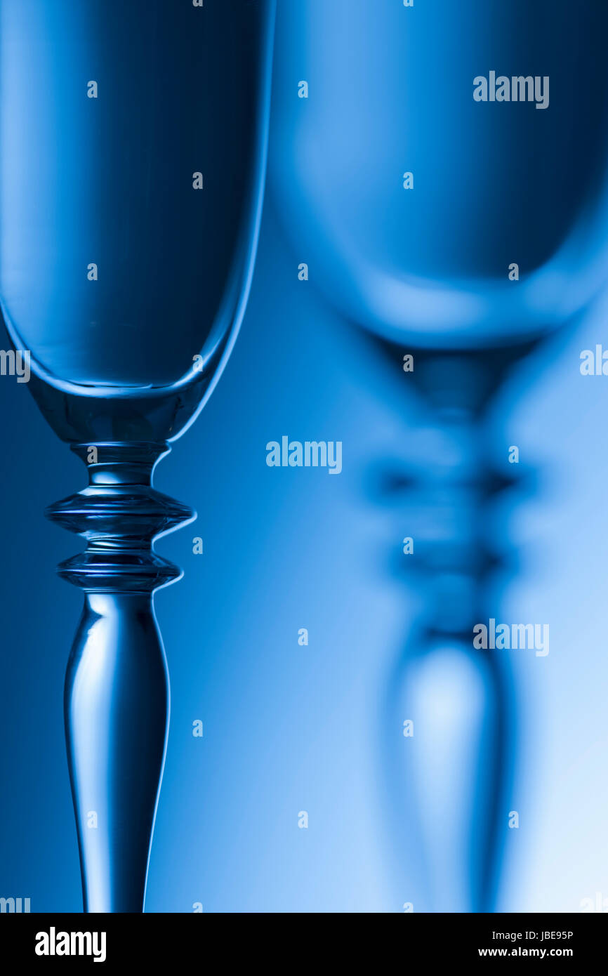 Detail-Ansicht Mittelteile zwieer Helligkeits Sektgläser der Hintergrund verlaufenden getont blau. Der Fokus liegt auf dem vorderen Glas. Banque D'Images