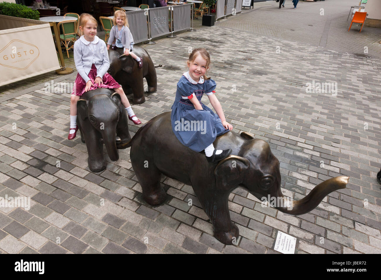 Enfants, jeunes, filles, ride et jouer sur la sculpture des Trois Grâces, par Philippa Downes