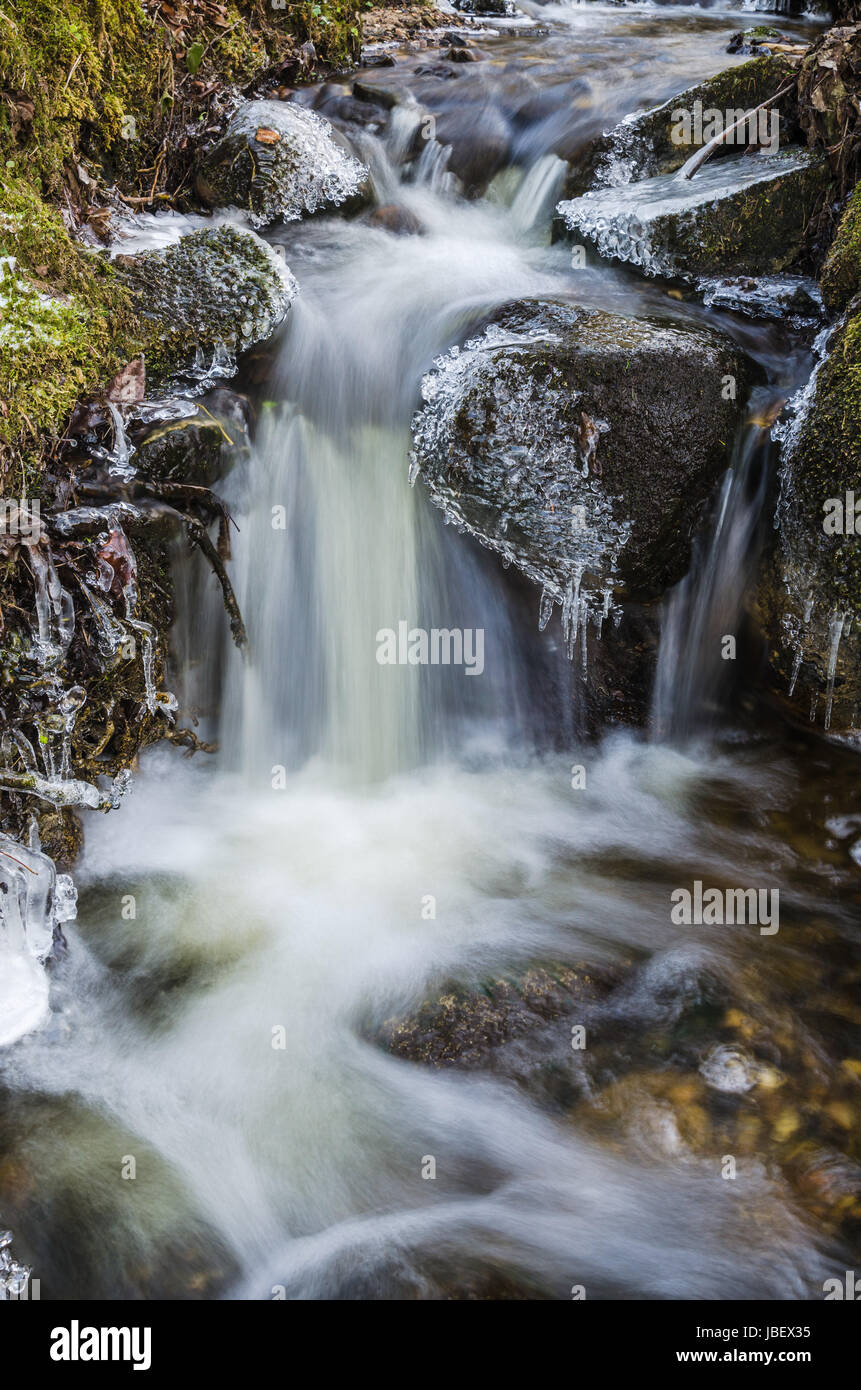 Petite cascade avec les glaçons et la glace de près, au printemps. Banque D'Images