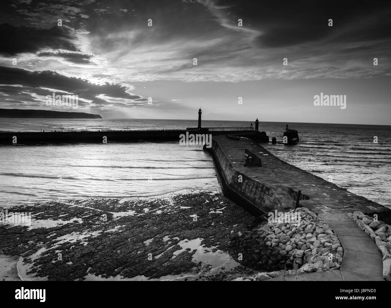 Whitby piers au crépuscule, le soleil ayant sur la mer du Nord. Banque D'Images