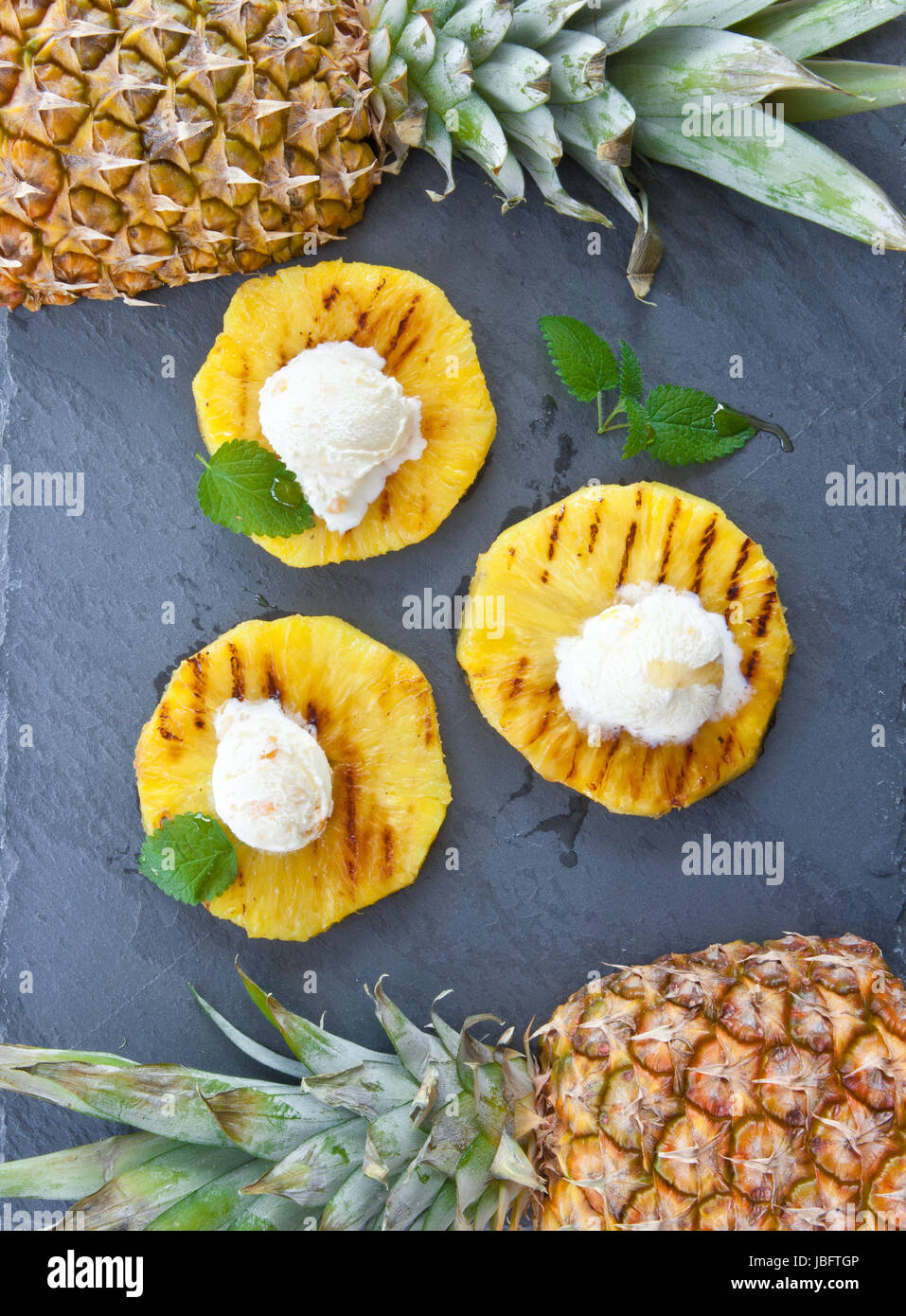 Gegrillete Eiscremekugeln Ananasringe mit Honig und auf Schieferplatte Banque D'Images