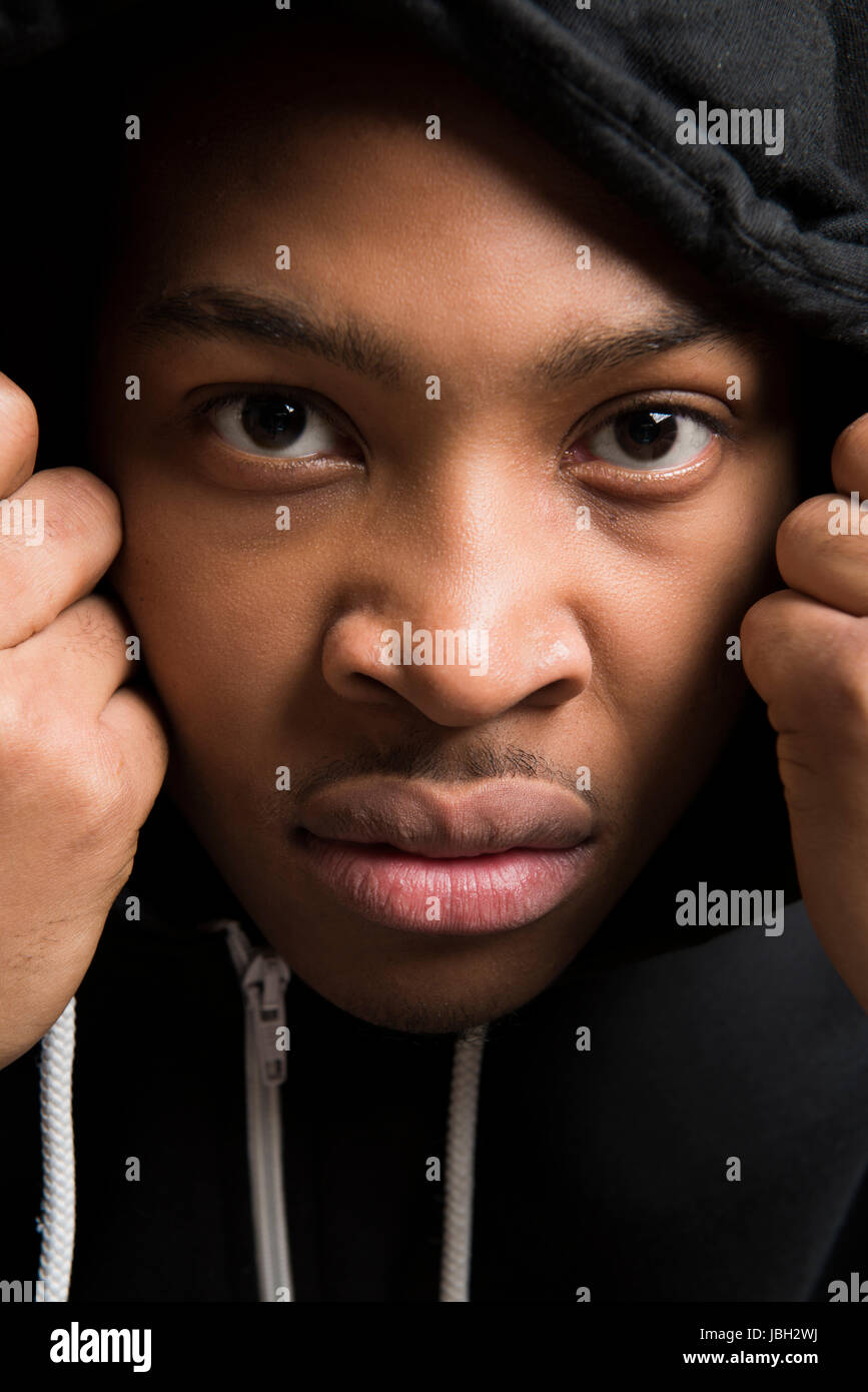 Portrait de teint foncé beau modèle masculin vêtu de noir avec capuchon Banque D'Images