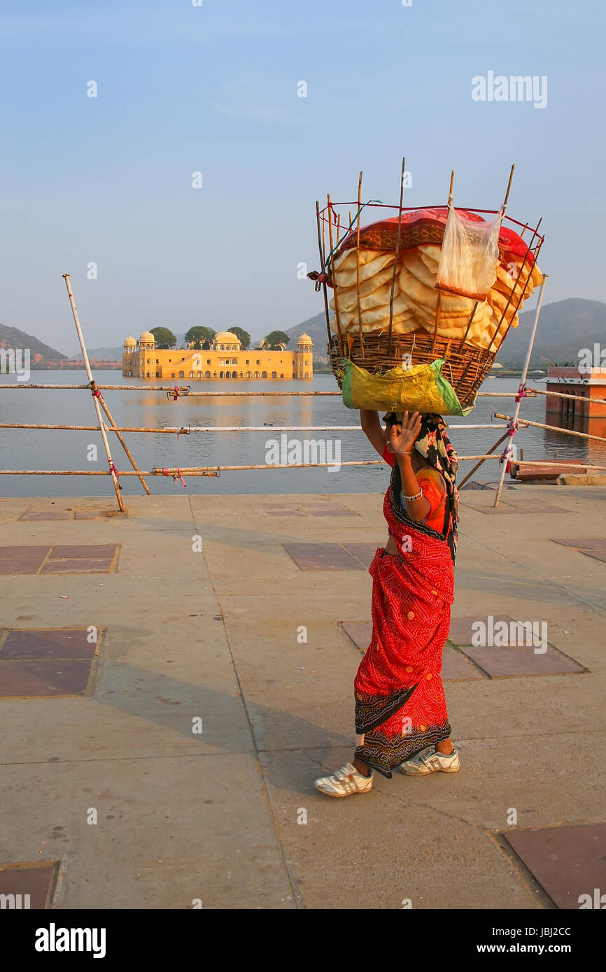 Femme indienne avec panier sur sa tête la marche par l'homme Sagar Lake à Jaipur, Rajasthan, Inde. Banque D'Images