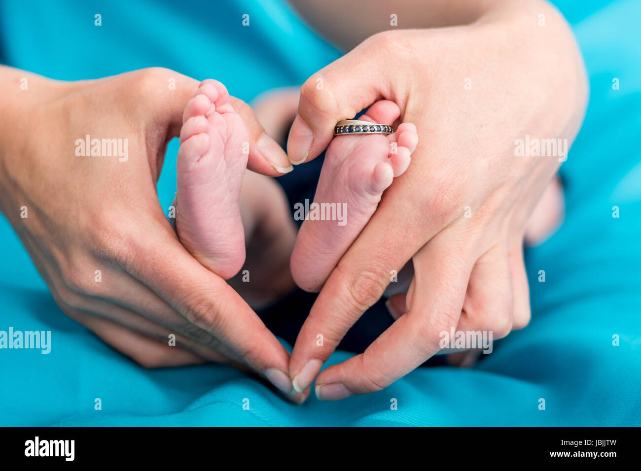 La mère mains formant un foyer autour de pieds de bébé. Banque D'Images