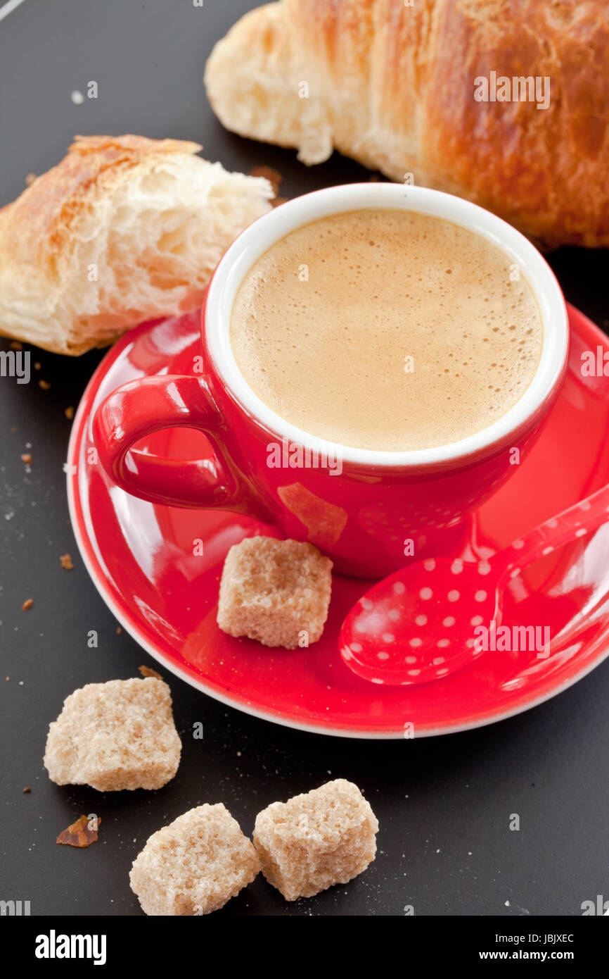 Rote Tasse mit Kaffee und ein Croissant auf Schwarz Banque D'Images