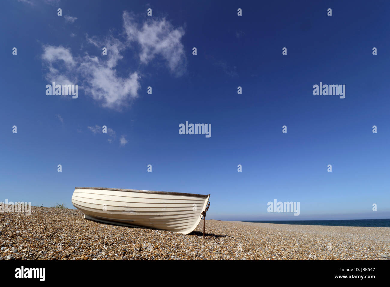 Petit bateau à rames tiré vers le haut sur la plage de galets à Salthouse Norfolk en Angleterre Banque D'Images