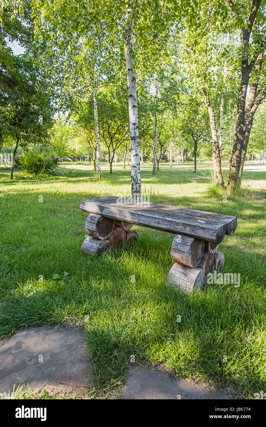 Vieux banc en bois fait à la main debout sur pelouse près de White Birch dans le parc ou le jardin, à partir de la droite de sentier de grès. Banque D'Images