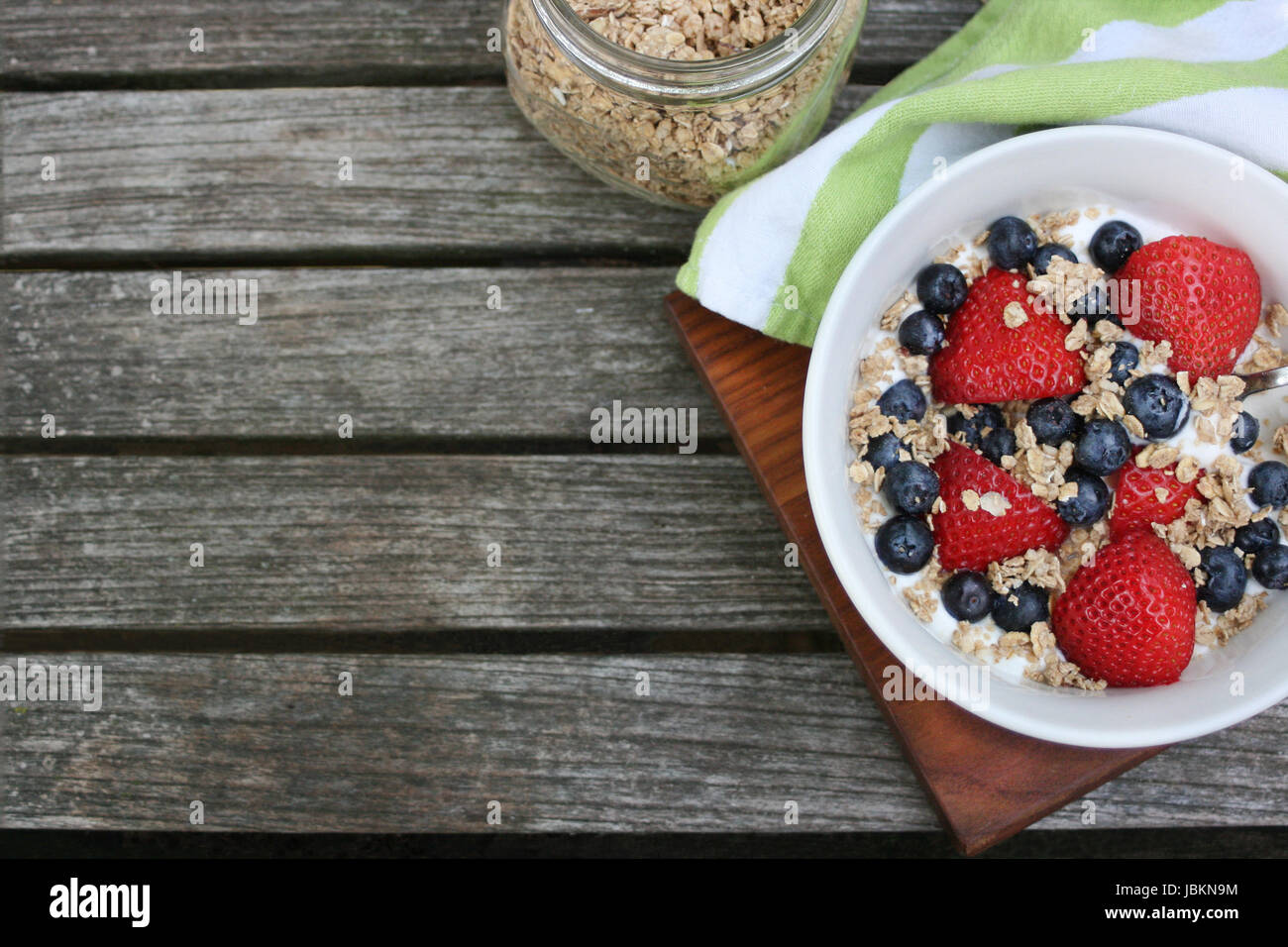 Petit-déjeuner sain bol. Dans un bol de granola blanc avec du yaourt grec et de baies sur fond de bois, vue du dessus, copy space Banque D'Images