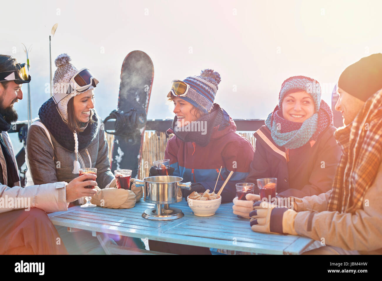 Snowboarder friends drinking cocktails sur balcon ensoleillé après-ski Banque D'Images