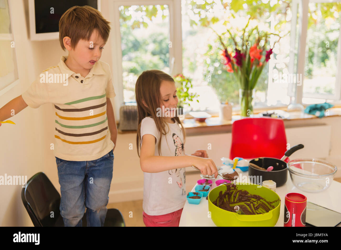Garçon et fille frère et soeur faire le chocolat cupcakes dans la cuisine Banque D'Images