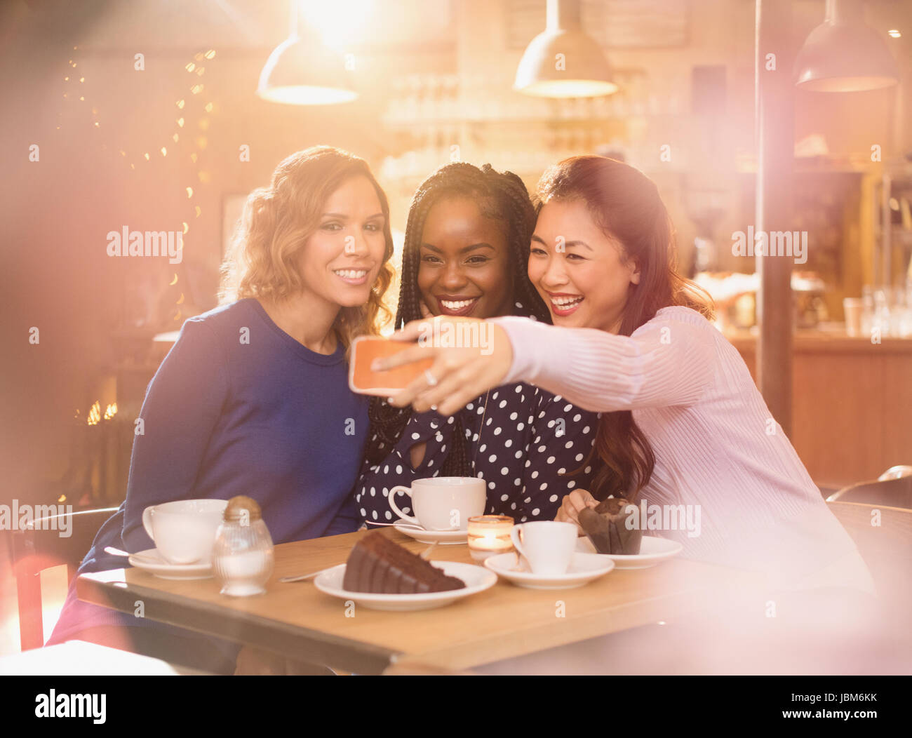 Smiling women friends avec selfies téléphone appareil photo au cafe table Banque D'Images