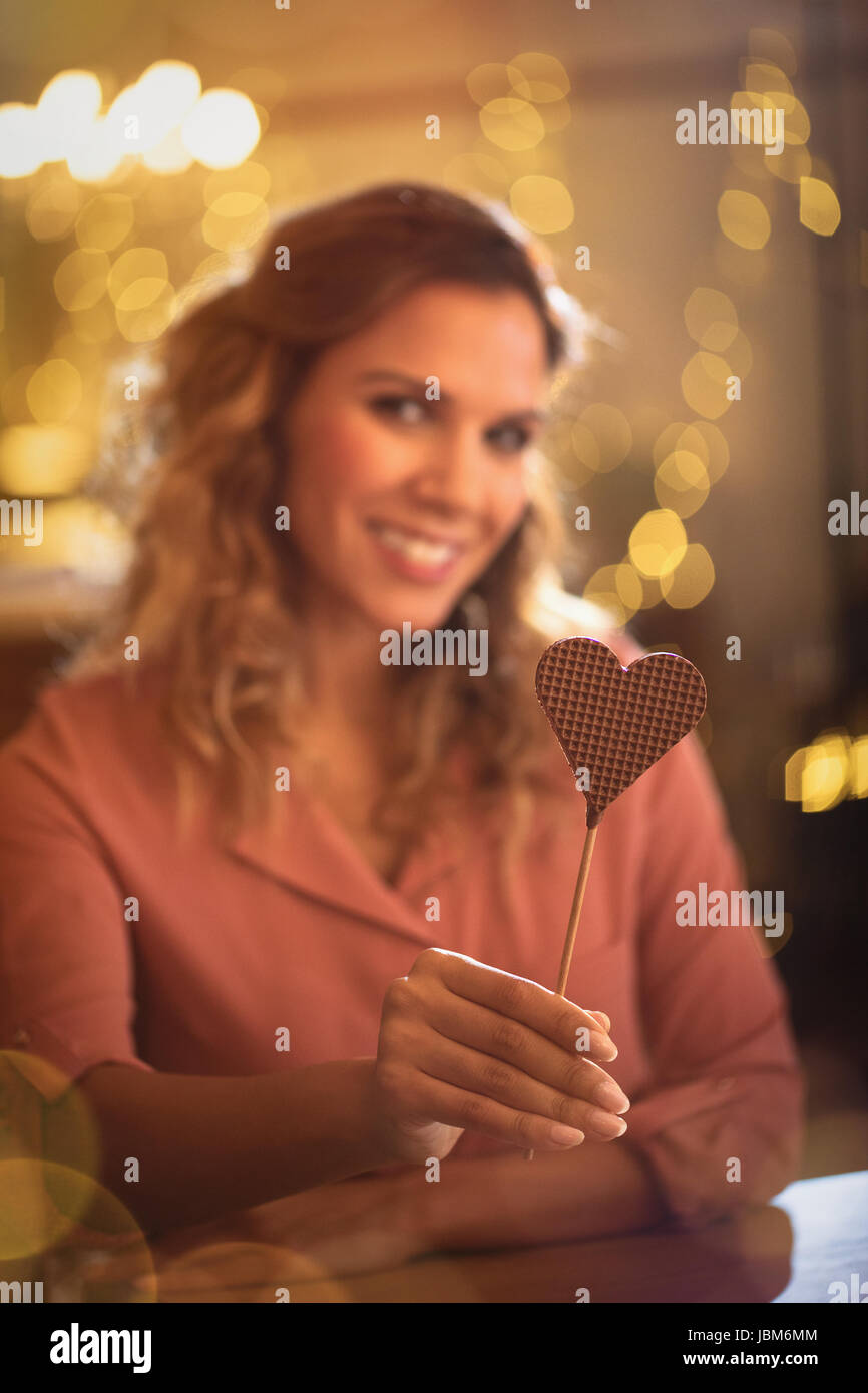 Portrait of smiling woman holding heart-shape lollipop Banque D'Images
