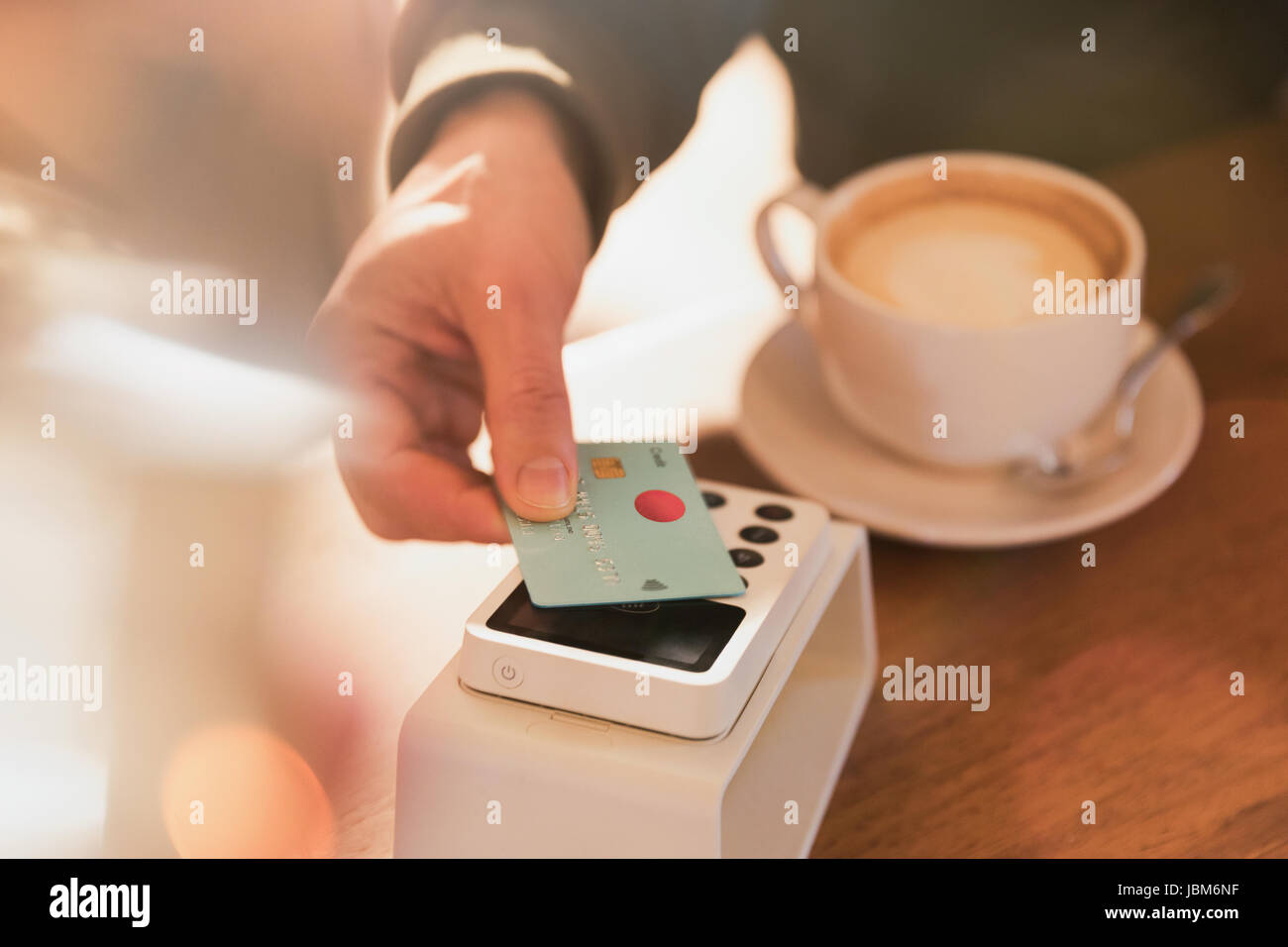 Close up man payer pour cappuccino avec carte de crédit paiement sans contact in cafe Banque D'Images