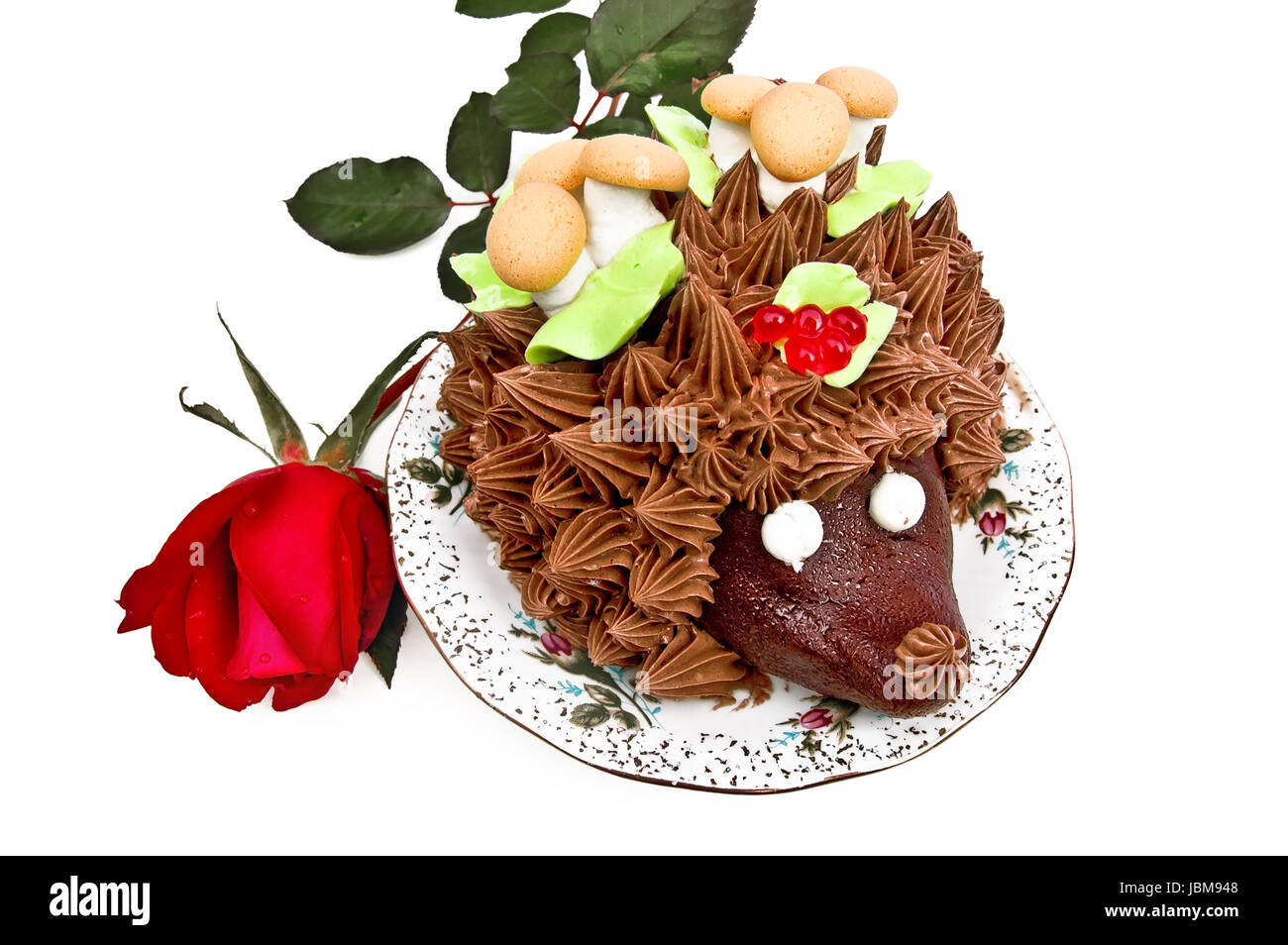 Gâteau à la forme d'un hérisson, ornée de feuilles vertes à la crème, les  champignons de la biscuiterie et de la meringue, de baies, de la vaseline  sur une plaque avec un