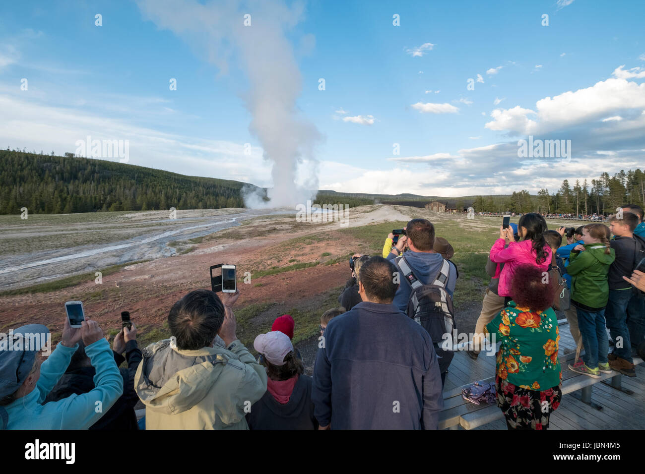 Les visteurs regardent l'éruption du geyser Old Faithful dans le parc national de Yellowstone, Wyoming, États-Unis. Banque D'Images