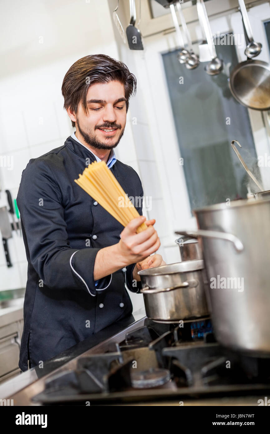 Junger koch bereitet frische von spaghetti pâtes suis troupeau au restaurant der küche zu Banque D'Images