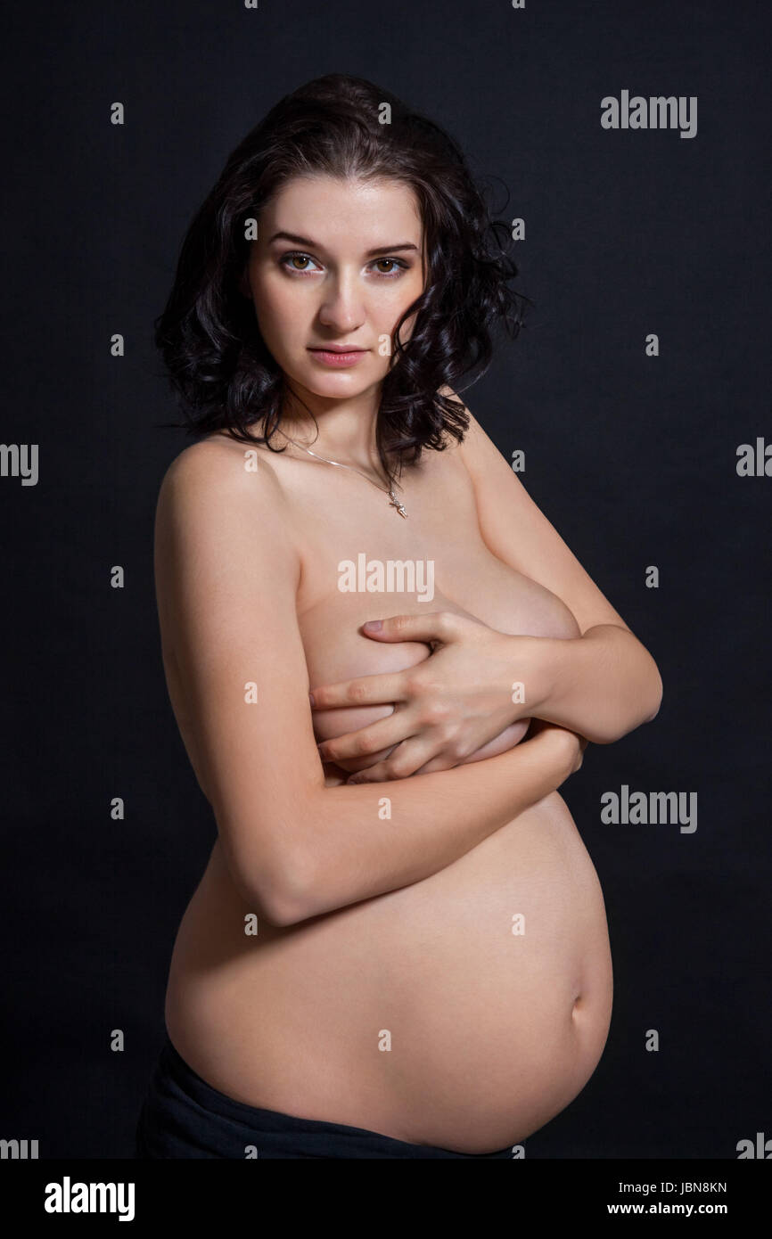 Schwangere Junge Frau mit schwarzem Hintergenund Babybauch vor nackt Banque D'Images