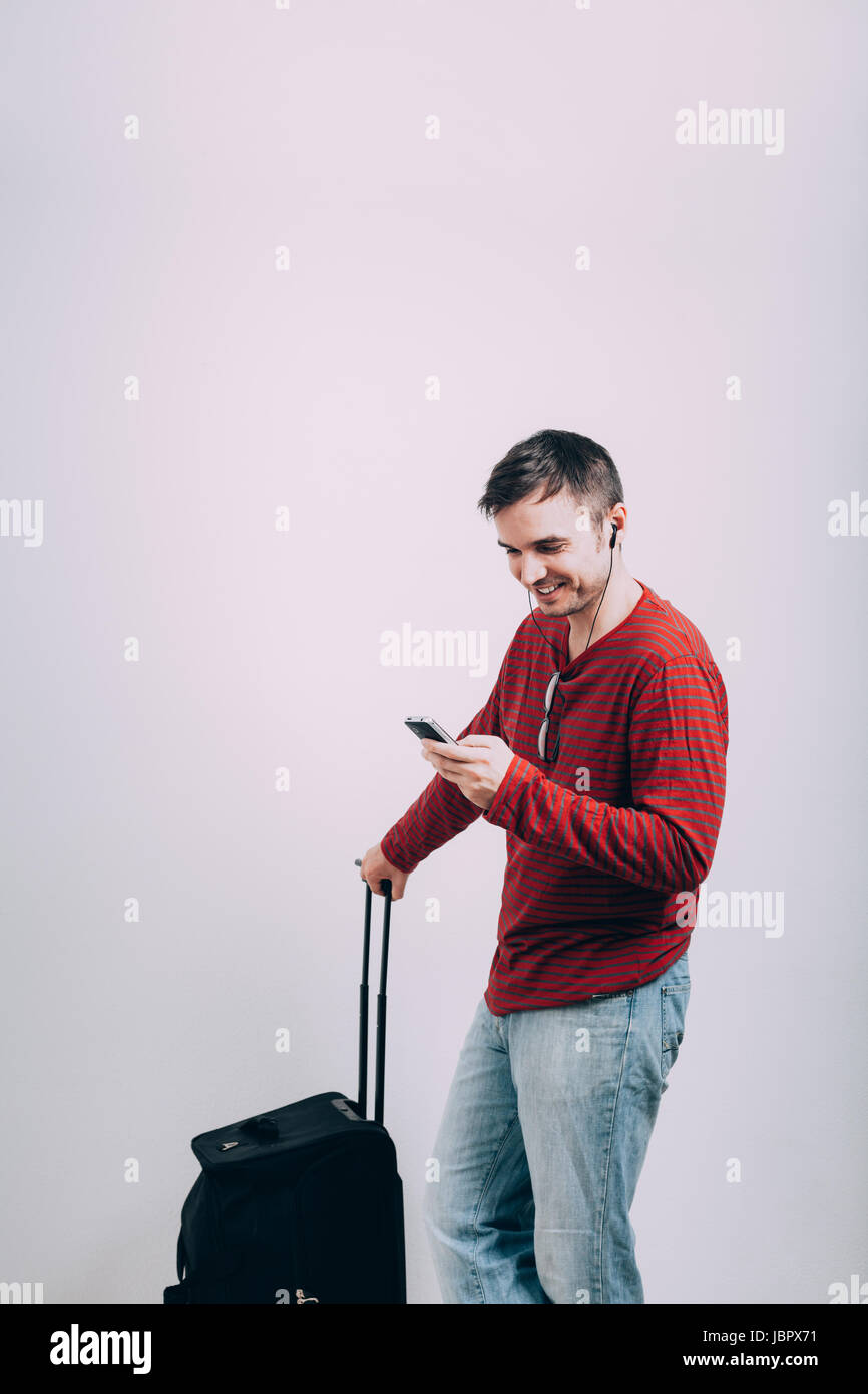 Heureux homme voyager avec des bagages et à l'aide de téléphone mobile. Banque D'Images