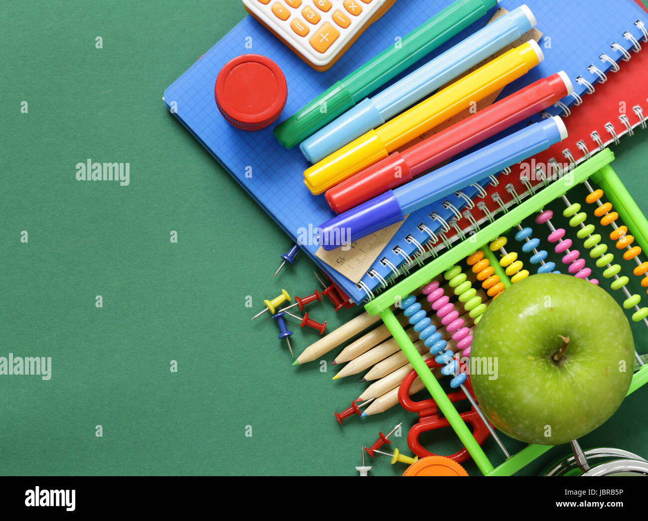 Fournitures scolaires et d'Apple sur un fond vert Banque D'Images