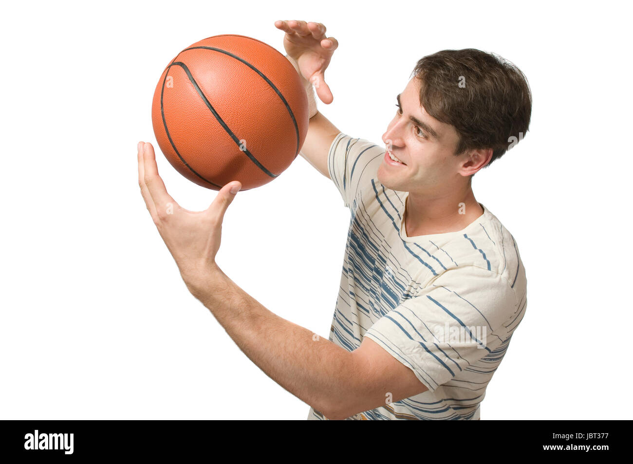 Oberkörper-Ansicht eines jungen Mannes im gestreiften T-Shirt weissen vor der Hintergrund und zufrieden jonglierend Basket-ball balle blickend auf den Banque D'Images